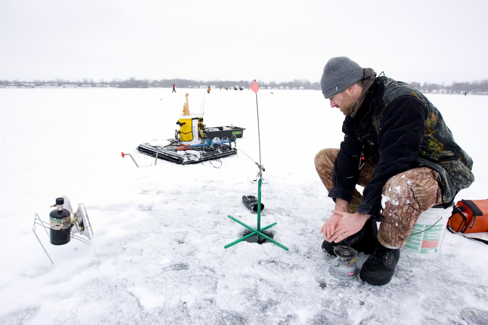 Man ice fishing on frozen lake