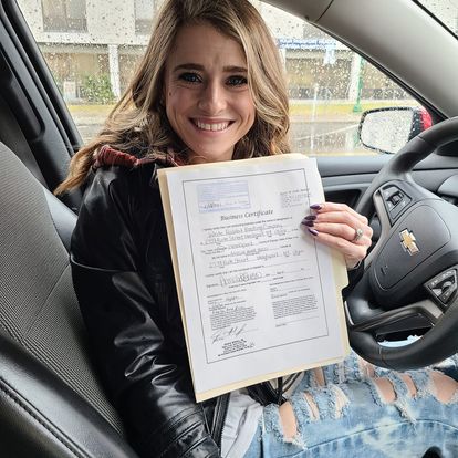 young women in a car holding an official document