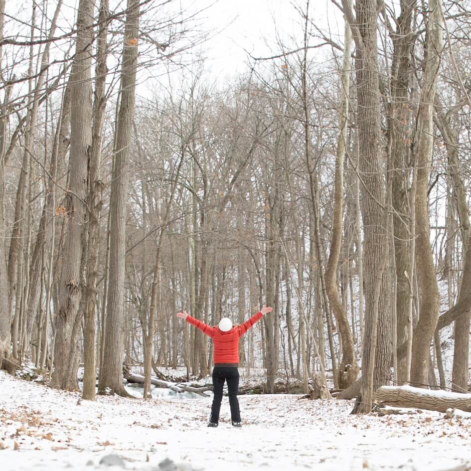 Person in a red coat walking in a snowy forest
