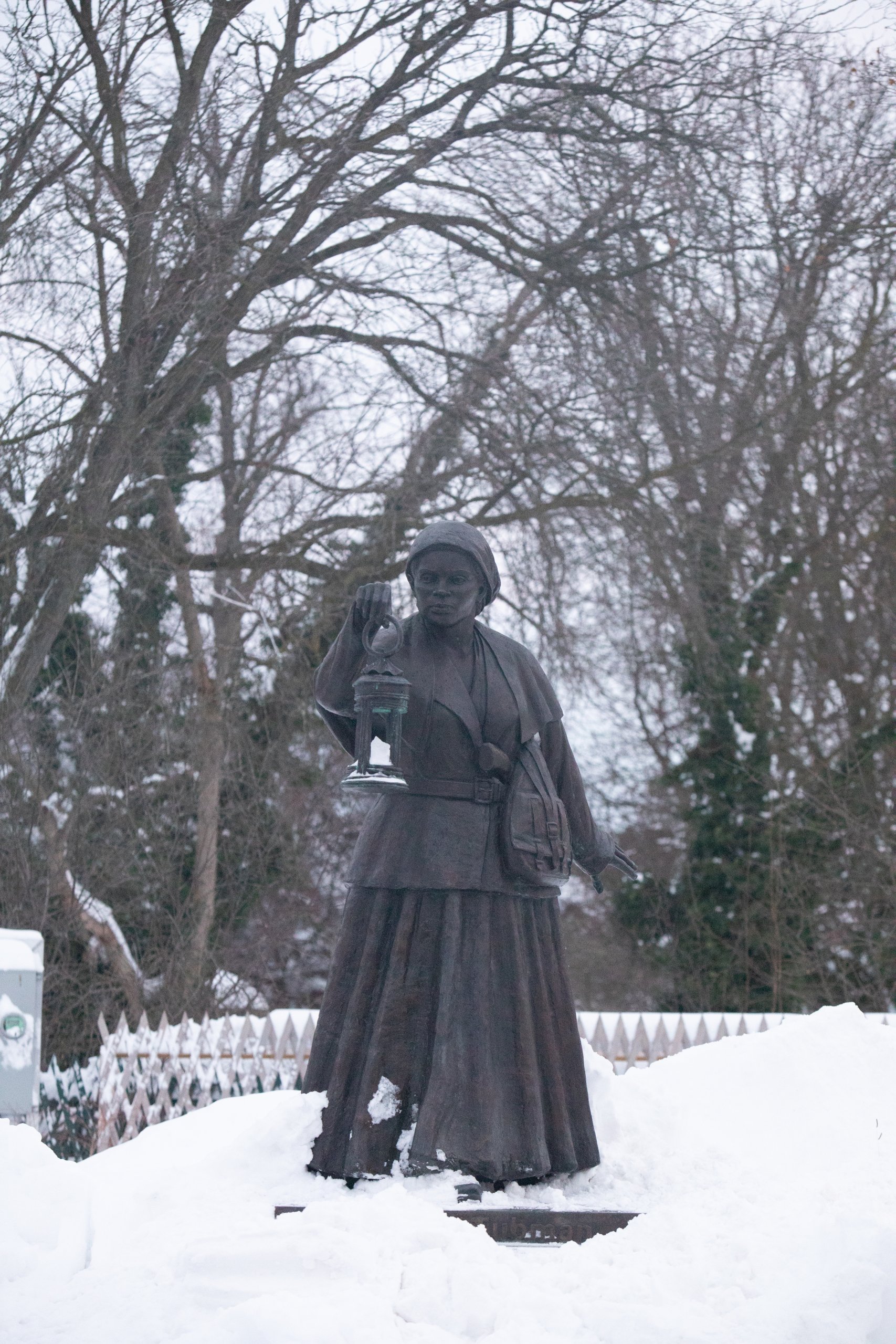 Bronze statue of Harriet Tubman surrounded by snow and bare trees 