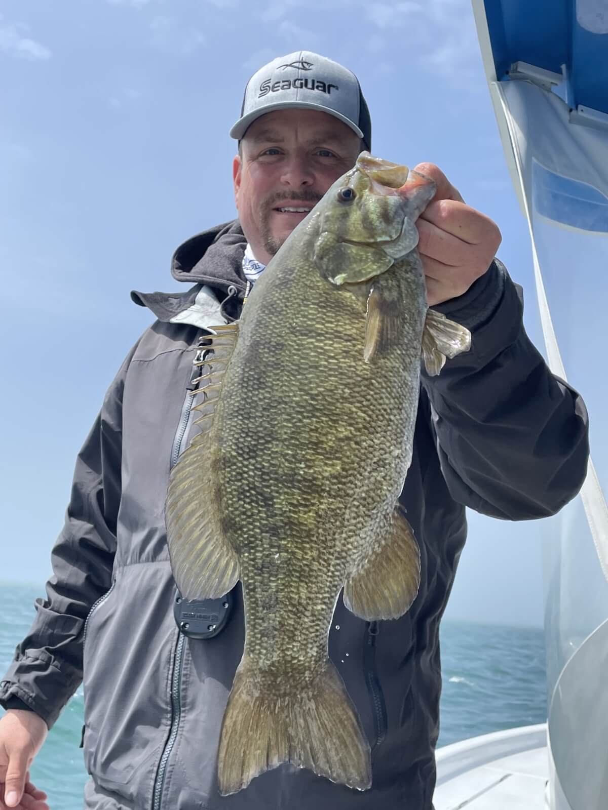 Man on a boat holding a  bass fish