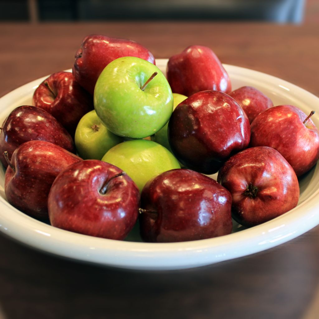 White bowl of red apples on a table that were freshly picked 
