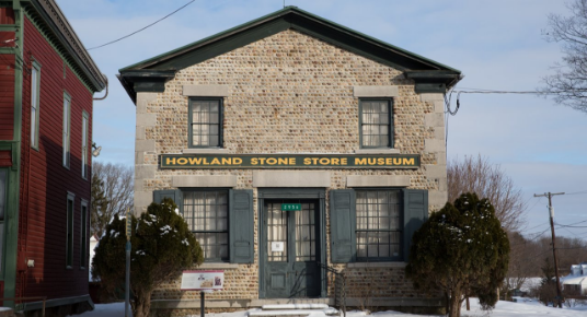 An old brick building with blue accents is labeled Howland Stone Store Museum.