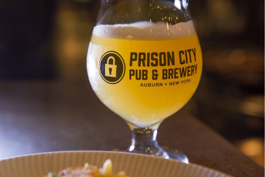 A glass of beer rests on a wooden bar at the Prison City Pub & Brewery
