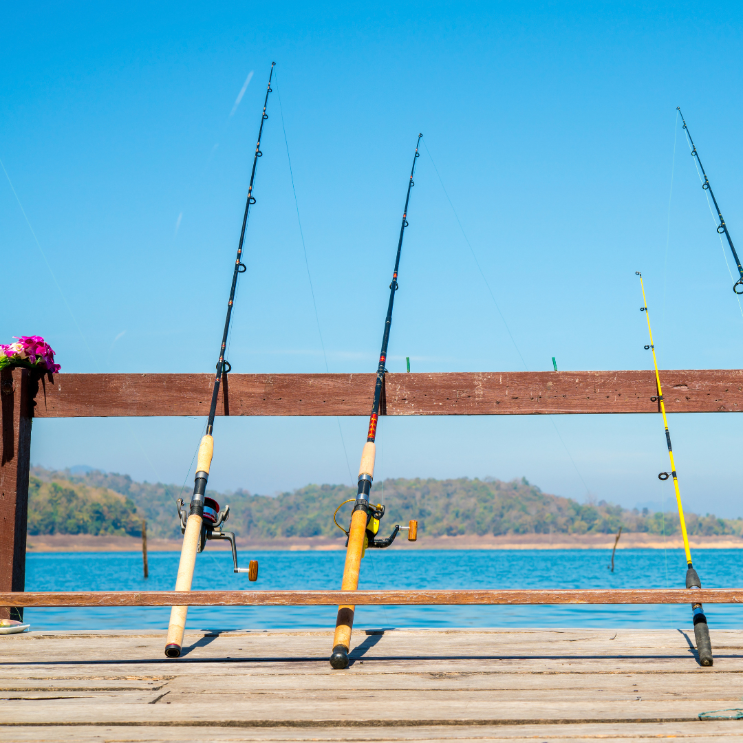 fishing poles leaning against a fence in front of a lake