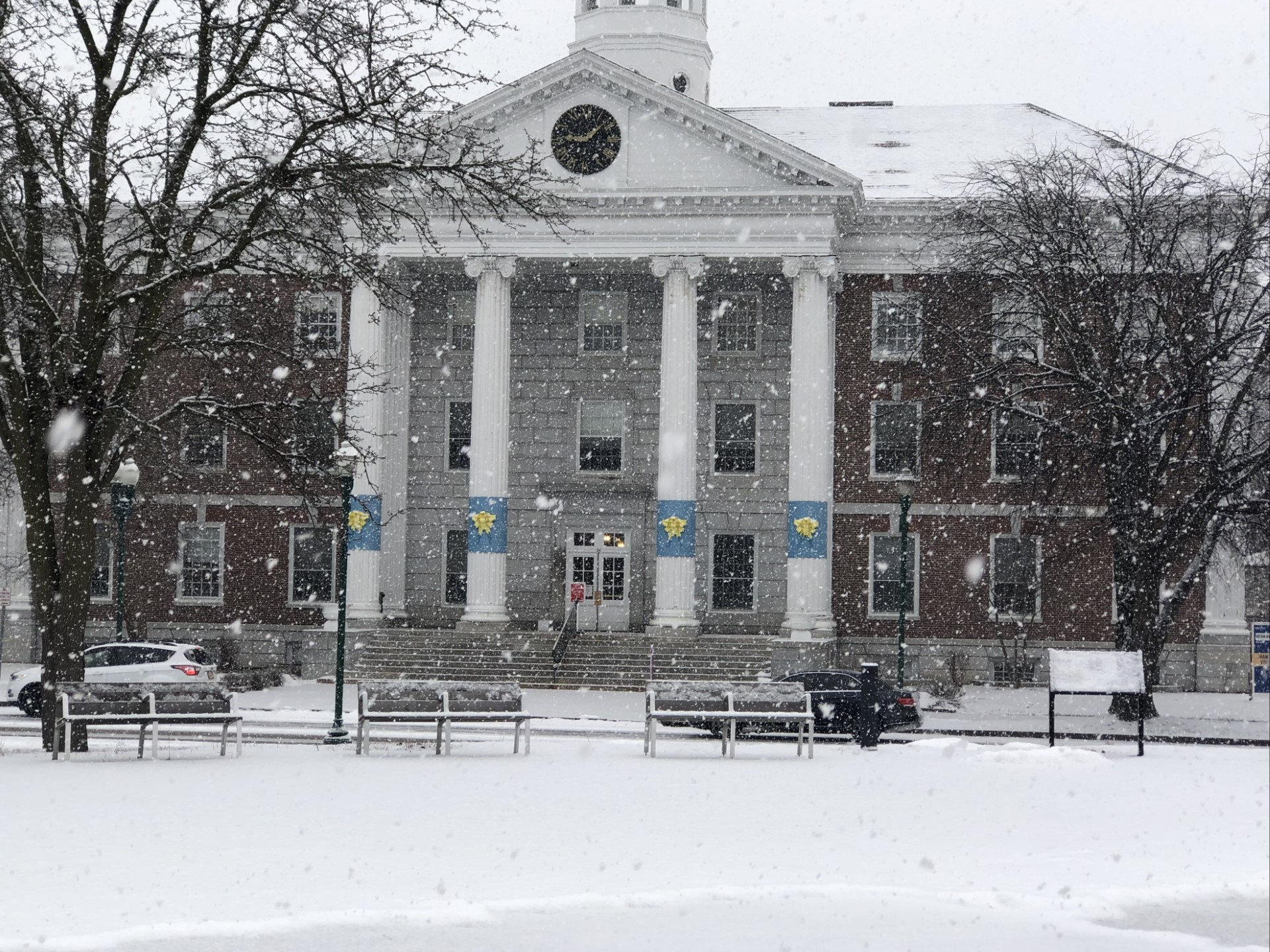 City Hall exterior of brick building with 4 white columns during a snow storm